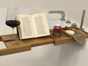 Badewannenablage mit Buch, Kerze und Weinglas