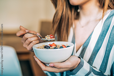 Junge Frau ist Müsli mit Obst