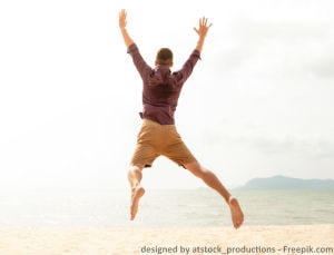 Junger Man springt vor Freude am Strand