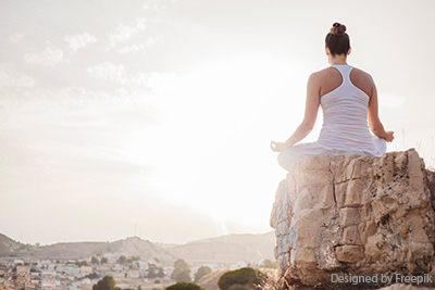 Junge Frau beim Yoga auf einem Felsen in der Natur