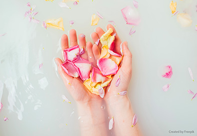 Hände in Handbad mit Blütenblättern